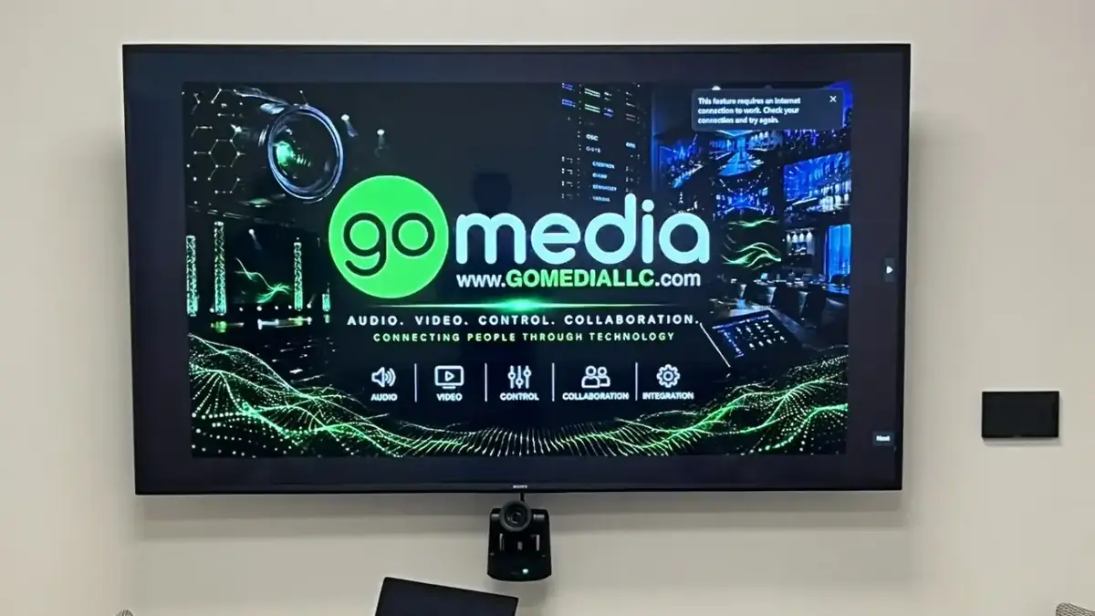 Video conferencing room with wall-mounted display and PTZ camera installed by Go Media